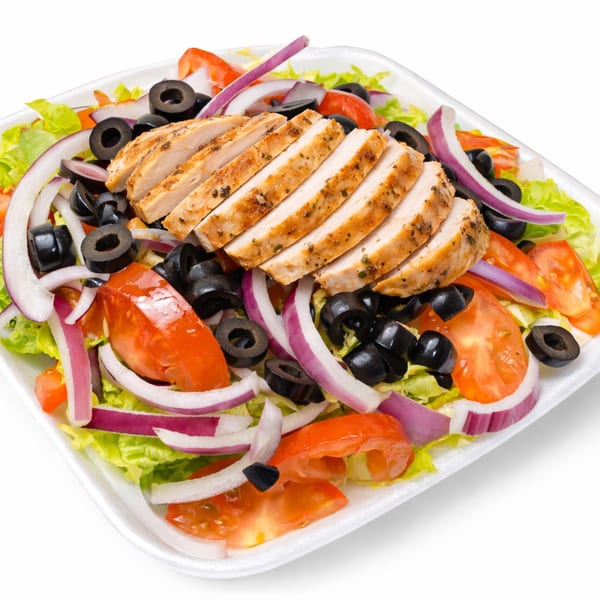 Grilled chicken salad with lettuce, tomatoes, red onions, and black olives in a white container.