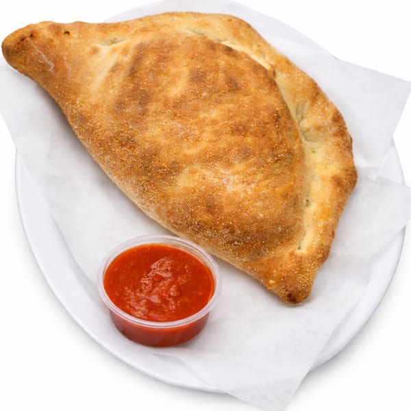 A golden-brown calzone from Rocco's NY Pizzeria & Pasta, served with a side of marinara sauce.